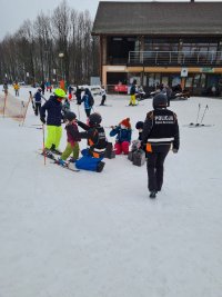 Policyjny patrol narciarski pełniący służbę na Górze Kamieńsk wręcza nagrody - kaski ochronne dzieciom, które wzięły udział w konkursie