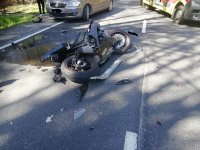 Motocykl leżący na jezdni po zderzeniu z osobówką