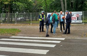 Policjanci oraz pracownik Urzędu Miasta w Radomsku i instruktor nauki jazdy rozmawiają z pieszymi oraz im wręczają odblaski pieszym.
