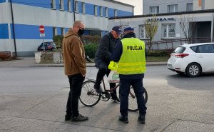 Policjanci wraz z pracownikiem Starostwa Powiatowego w Radomsku wręczają kamizelki odblaskowe w rejonie placu targowego w Kamieńsku.
