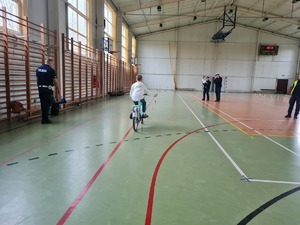 Uczestnik turnieju jedzie na rowerze . Policjant Ruchu drogowego .