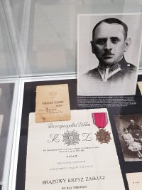 Zdjęcie przedstawiające jednego z zamordowanych Policjantów oraz książeczka wojskowa i odznaczenie Brązowy Krzyż Zasługi