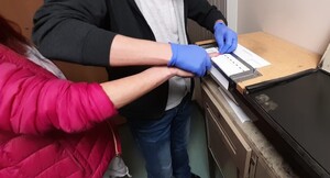 Technik kryminalistyki pobiera odciski linii papilarnych zatrzymanej kobiety