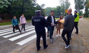 Policjanci oraz pracownik Urzędu Miasta w Radomsku i instruktor nauki jazdy rozmawiają z pieszymi oraz im wręczają odblaski pieszym.