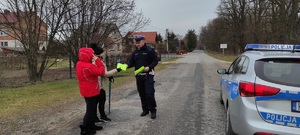 Policjant przekazuje kamizelkę odblaskową