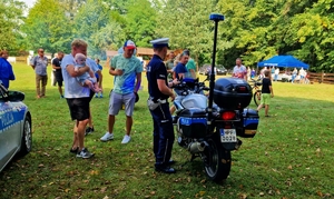 Policjant, policyjny motocykl oraz uczestnicy spotkania.