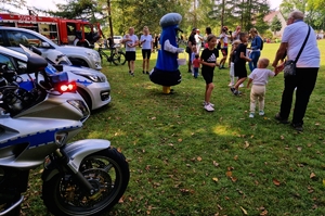 Policjant, policyjny motocykl oraz uczestnicy spotkania.