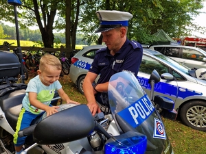 Policjant, policyjny motocykl oraz uczestnicy spotkania.