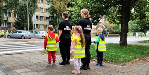 Uczennice klasy mundurowej przeprowadzają dzieci przez przejście dla pieszych.
