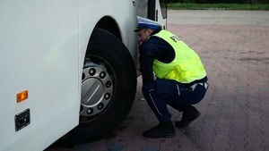 Policjant dokonujący kontroli autokaru.